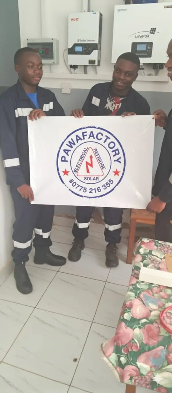 Pawafactory team members holding a banner with the company logo and phone number in front of installed inverters